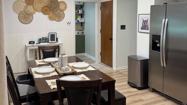 A modern kitchen with a stainless steel refrigerator, wooden dining table with chairs, and recessed ceiling lights. - 4BR Home - Airport- UD - WPAFB - POOL -Sleeps 7 (Dayton)