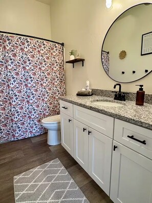 Un bagno con il water, un lavandino con specchio e una tenda da doccia con motivo floreale.