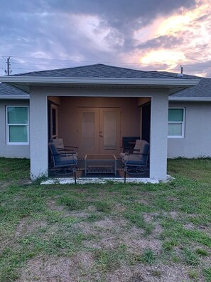 A house with a covered porch, two chairs, a table, and a door. - Beautiful home near Warm Springs (North Port)