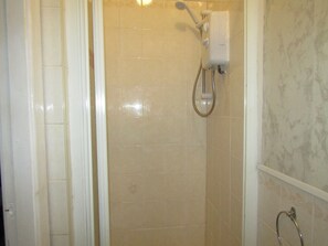 Un baño con ducha, paredes de azulejos y un inodoro.