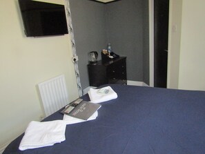 A hotel room with a bed, a bedside table, a remote control, and a water bottle. - No 12 GuestHouse (Blackpool)
