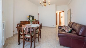 A dining area with a table and chairs, a chandelier, a sofa, and a door leading to another room. - Nacci White Home by Rentbeat (Ostuni)