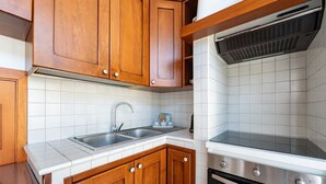 A kitchen with wooden cabinets, a stainless steel sink, and a built-in oven. - Nacci White Home by Rentbeat (Ostuni)
