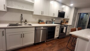 Una cucina moderna con mobili bianchi, elettrodomestici in acciaio inossidabile e pavimento in legno.