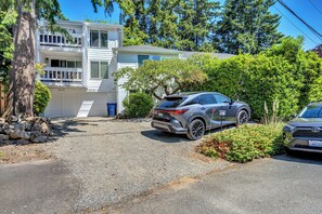 A two-story house with a garage, a driveway, and a parked SUV. - Cozy 2-bedroom condo in tranquil Kirkland with workspace (Kirkland)