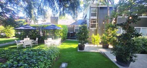 Ein gepflegter Garten mit Terrasse, Gartenmöbeln und Kübelpflanzen.