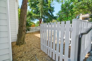 A white wooden fence with vertical slats, a tree, and a mulched ground area. - Cozy 2-bedroom condo in tranquil Kirkland with workspace (Kirkland)
