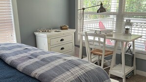 A bedroom with a bed, a desk, and a window.