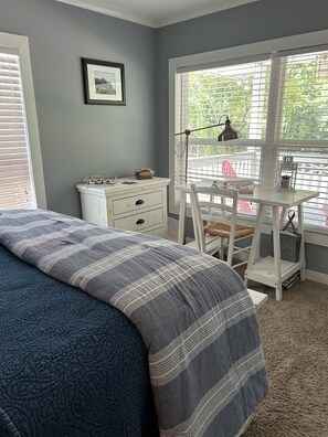 Un dormitorio con cama, escritorio y ventana.