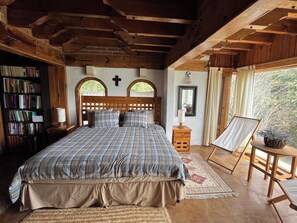 A wooden-framed bedroom with a bed, a bookshelf, a nightstand, a mirror, and a window with a view. - House with a spectacular view of the lake, 8 minutes from the Zócalo and downtown. (Valle de Bravo)