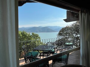 A balcony with a table and chairs, overlooking a body of water and distant mountains. - House with a spectacular view of the lake, 8 minutes from the Zócalo and downtown. (Valle de Bravo)