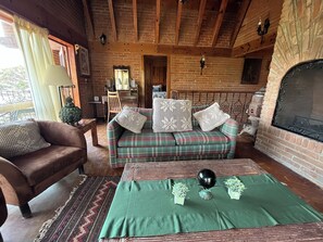 A cozy living room with a plaid sofa, a green rug, and a fireplace. - House with a spectacular view of the lake, 8 minutes from the Zócalo and downtown. (Valle de Bravo)