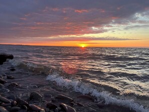 Um pôr do sol sobre uma costa rochosa com ondas.
