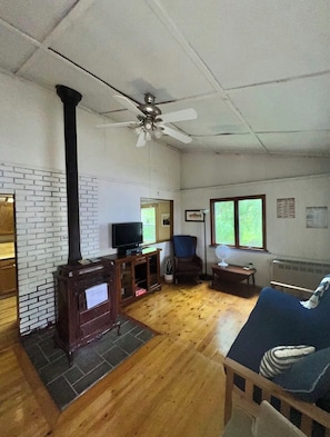 Uma sala de estar com lareira, televisão e ventilador de teto.