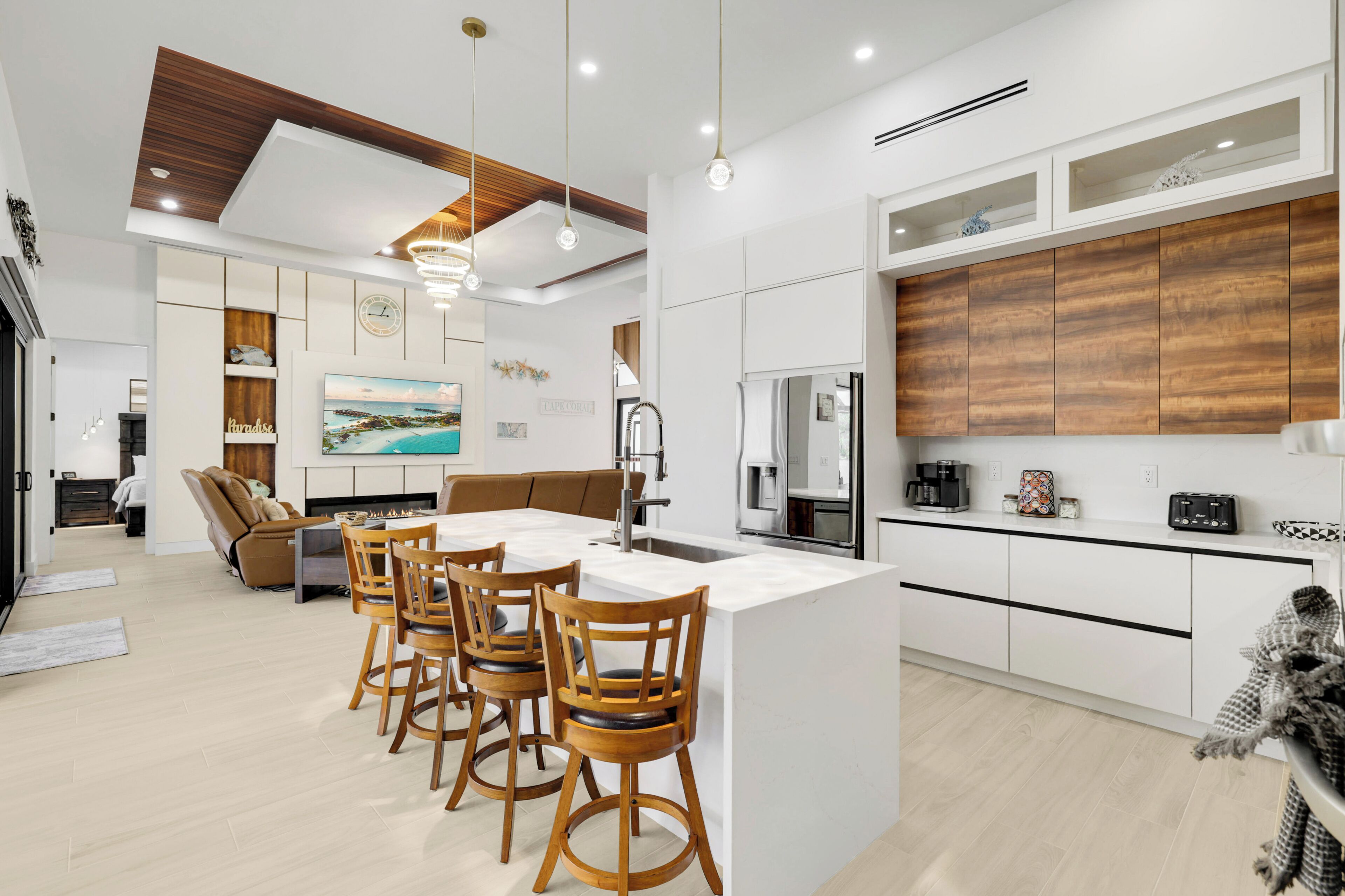 A modern kitchen with a central island, bar stools, a dining area with a sofa, and a large painting on the wall.