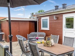 En uteplats med ett bord, stolar och en grillplats.