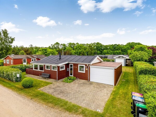 Ett enplanshus med garage, omgivet av välskötta gräsmattor och häckar.