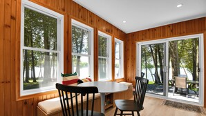 Una habitación con ventanas amplias, interior de madera, una mesa redonda y un banco.