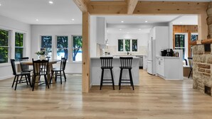 Una cocina moderna con armarios blancos, una isla central y una chimenea de piedra.