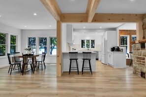A modern kitchen with white cabinetry, a central island, and a stone fireplace.