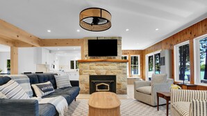 Una sala de estar moderna con chimenea de piedra, un televisor de pantalla plana y piso de cuadros.