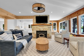 A modern living room with a stone fireplace, a flat-screen TV, and a checkered floor.