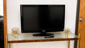 Un televisor sobre un mueble de vidrio y metal, con un control remoto.