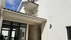 Un edificio con techo de tejas, puerta de entrada de vidrio y un patio con suelo de piedra.