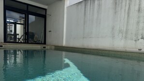 Una piscina interior con agua cristalina, suelo de baldosas y pared de hormigón.