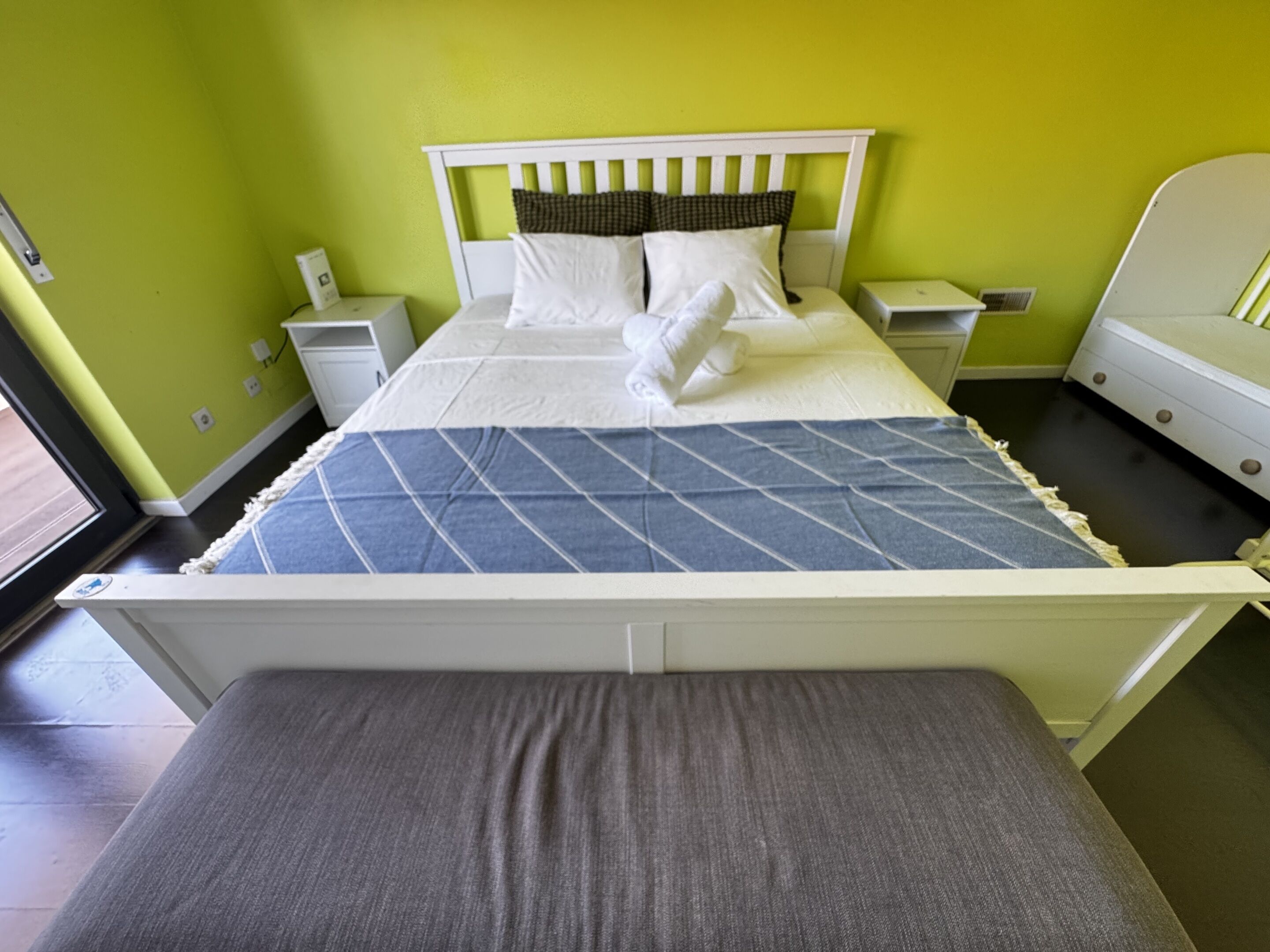 Una cama con cabecera blanca, colchón gris y colcha azul acolchada.