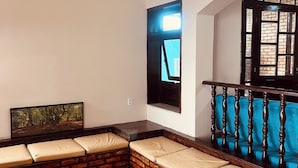A room with a brick bench, a wooden railing, and a hanging light fixture. - Zyra's House in Villas - 12 min from the Airport (Lauro de Freitas)