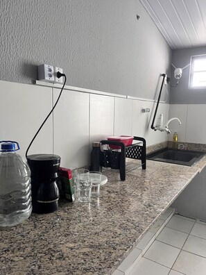 Eine Küche mit Granit Arbeitsplatten, einer Kaffeemaschine, einem Wasserspender, einem Spülbecken und einer Überwachungskamera.