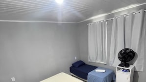 A room with two beds, a fan, a small cabinet, and a window with curtains. - Zyra's House in Villas - 12 min from the Airport (Lauro de Freitas)