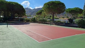 An outdoor tennis court with trees and mountains in the background. - Bed Breakfast Villa Saracina (Lipari)
