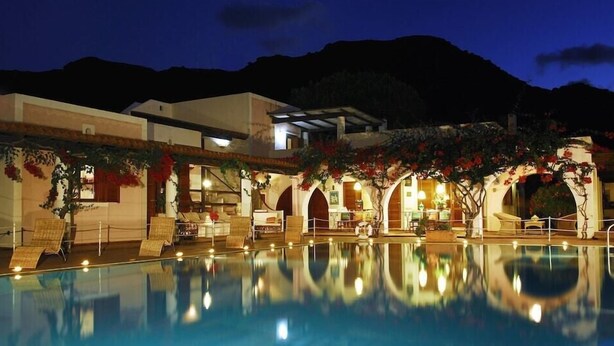 A pool area with a clear view of the pool, a covered seating area, and a mountain backdrop. - Bed Breakfast Villa Saracina (Lipari)