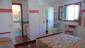 A bedroom with two beds, a bathroom, a mirror, and a chair. - Bed Breakfast Villa Saracina (Lipari)