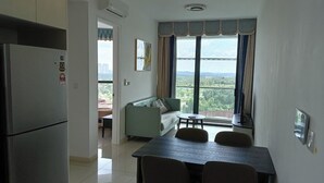 A compact kitchen with a refrigerator, a dining table with chairs, a sofa, and a large window with curtains. - legoland luxury homestays by NLA (Iskandar Puteri)