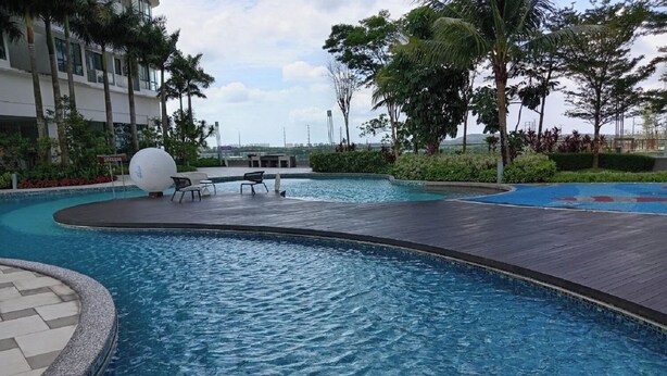 A swimming pool with a curved edge, lounge chairs, and a small table. - legoland luxury homestays by NLA (Iskandar Puteri)