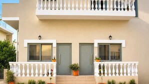 Ein zweistöckiges Gebäude mit Balkon, zwei Türen und Blumentöpfen.