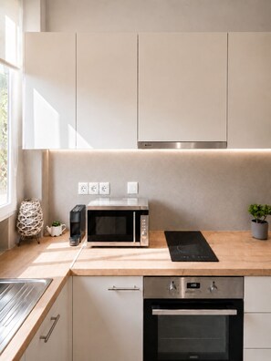 Eine moderne Küche mit eingebauter Mikrowelle, Backofen und einer Holz Arbeitsplatte.