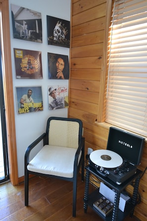 Een kamer met houten wanden, een stoel, een draaitafel en wanddecoratie.