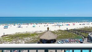 Een strand met een rieten hut, ligbedden en parasols.