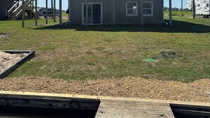 A two-story building with a balcony, a dock, and a grassy area. - Lake Life Starts Here—w/ Dock, Kayaks & Relaxation (Craig)