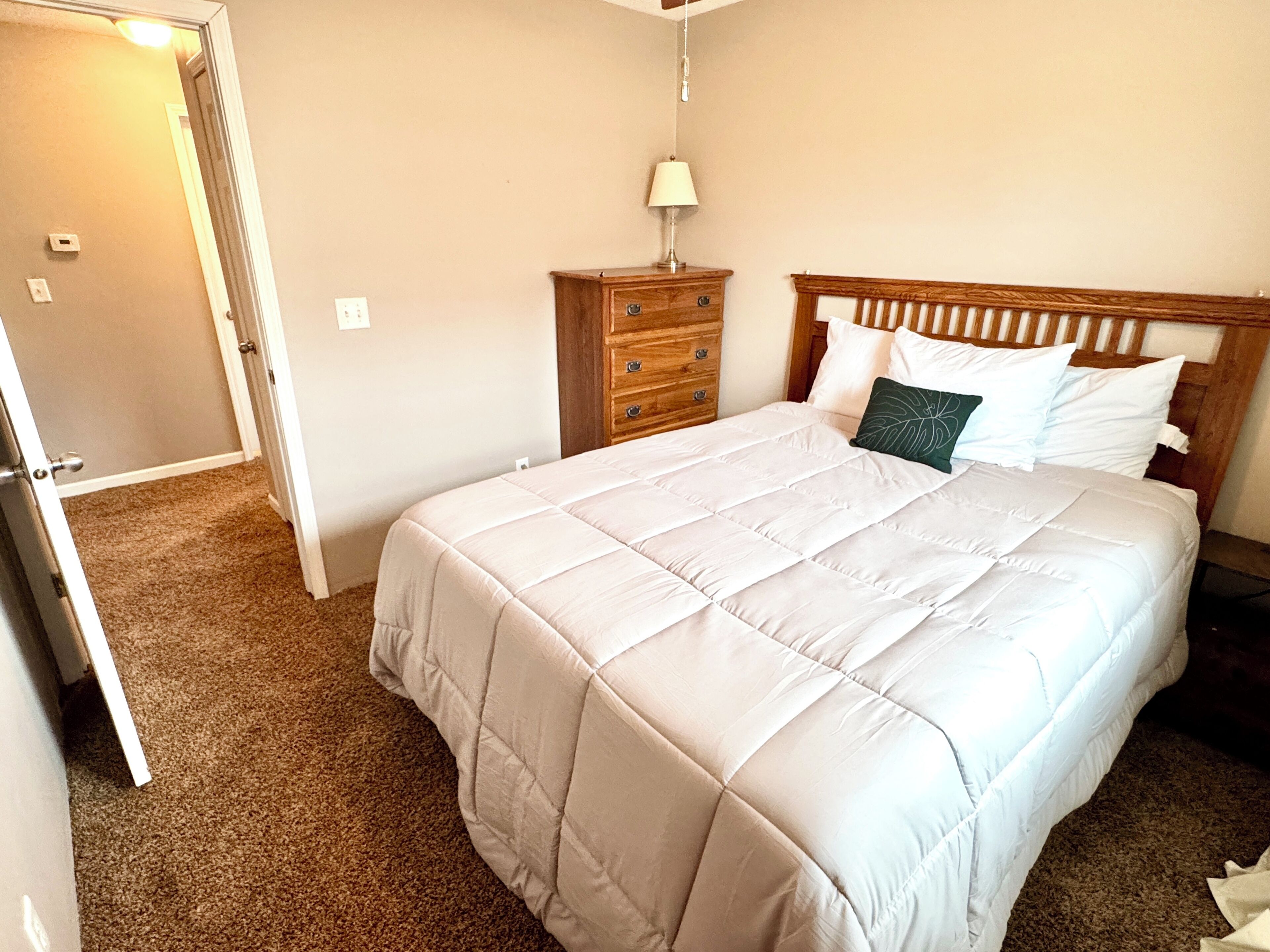 A bedroom with a bed, a nightstand, a lamp, and a door.