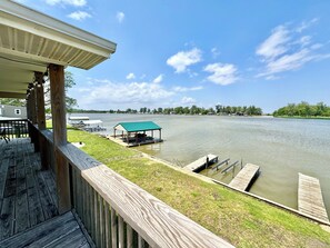 Une terrasse en bois surplombant un lac paisible, avec des quais et un pavillon abrité.