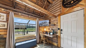 A wooden interior with a desk, chair, and a view of a lake through a window. - Harvey’s River Retreat 30 minutes from Yellowstone (Island Park)