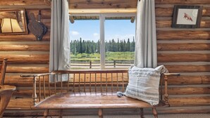 A wooden cabin interior with a bench, a window with curtains, and a framed picture on the wall. - Harvey’s River Retreat 30 minutes from Yellowstone (Island Park)