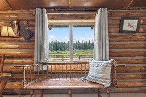 A wooden cabin interior with a bench, a window with curtains, and a framed picture on the wall. - Harvey’s River Retreat 30 minutes from Yellowstone (Island Park)