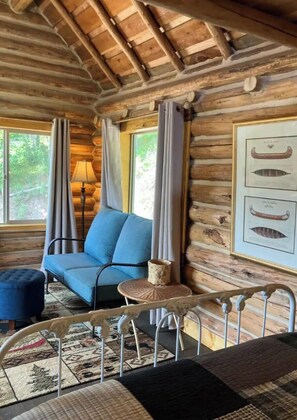 A log cabin interior with a sofa, a small table, and a chair. - Harvey’s River Retreat 30 minutes from Yellowstone (Island Park)