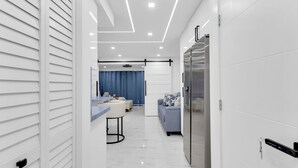 Una cocina moderna con refrigerador, un comedor con mesa y sillas, y una sala de estar con sofá.